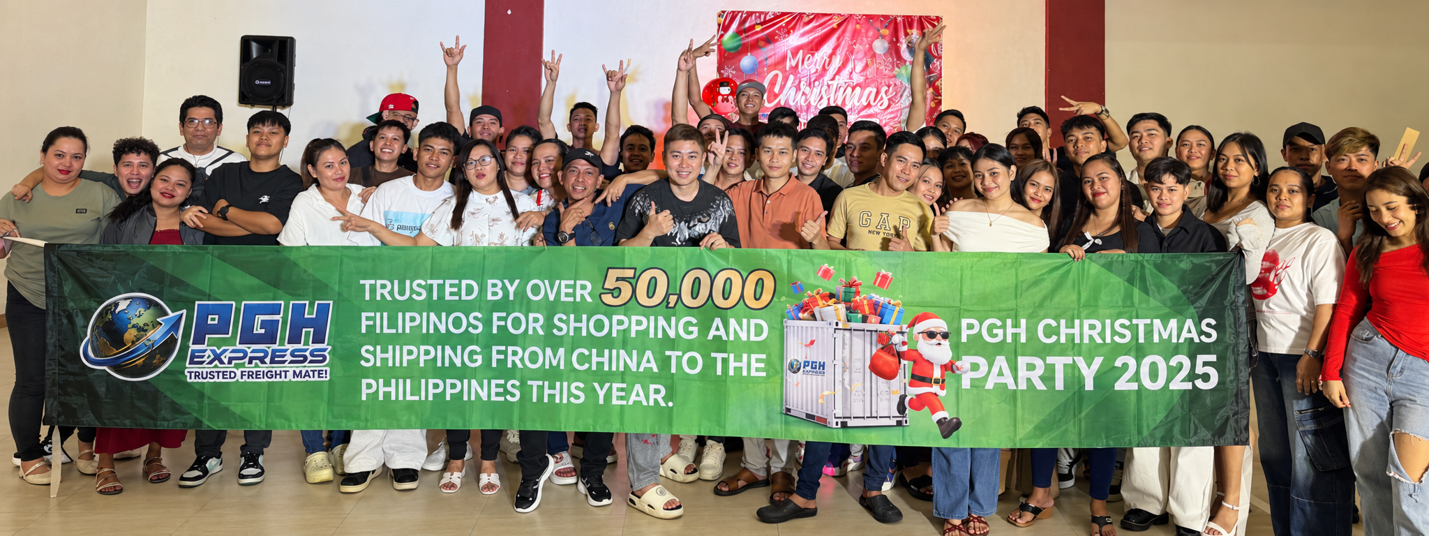 PGH team gathered behind a green banner at the 2025 Christmas celebration